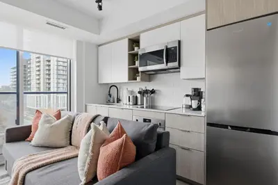 a living room with a couch and a kitchen at Cozy 2BR Condo with Free Parking & City Views in Toronto
