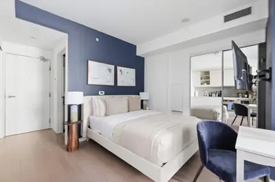 a bedroom with a white bed and a blue wall at Chic Downtown TO Studio Near Entertainment Dist in Toronto