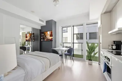 a white bedroom with a large bed and a table at Chic Downtown TO Studio Near Entertainment Dist in Toronto