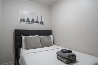 a bedroom with a white bed with a black headboard at Stylish Modern Condo in the Heart of Toronto in Toronto