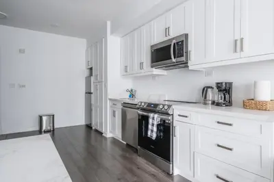 a kitchen with white cabinets and a stove top oven at Stylish Modern Condo in the Heart of Toronto in Toronto