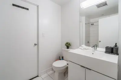 a white bathroom with a toilet and a sink at Stylish Modern Condo in the Heart of Toronto in Toronto