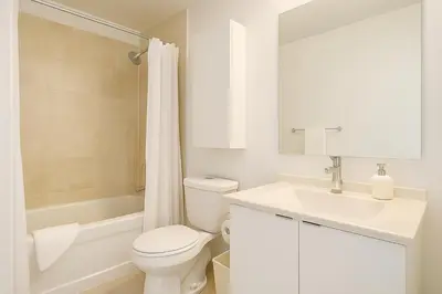 a white bathroom with a toilet and a sink at 60th Floor Luxury SkySuite 3BD Lake & City Views in Toronto