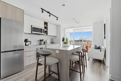 a kitchen with white cabinets and bar stools at Modern West Getaway 2BR Condo with Free Parking in Toronto