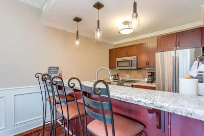 a kitchen with a counter with three chairs at it at The Sweet Spot - Walk to Village & Hot Tub in Blue Mountains