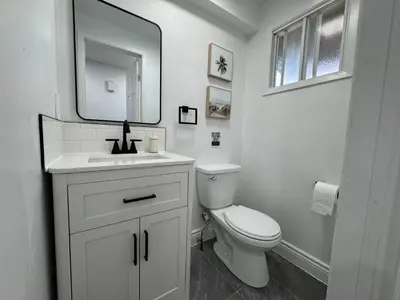 a white bathroom with a toilet and a mirror at North Barrie !D Stylish and Cozy Private Bedroom with Shared Bathroom in Barrie