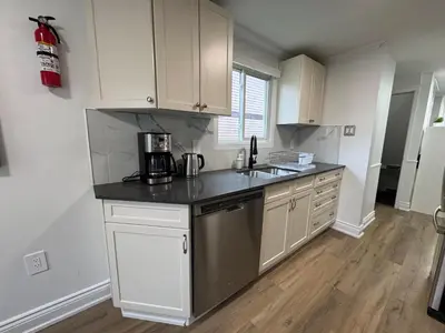 a kitchen with white cabinets and a black counter top at North Barrie !D Stylish and Cozy Private Bedroom with Shared Bathroom in Barrie
