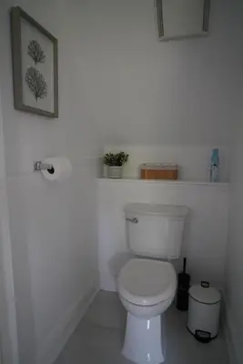 a white bathroom with a toilet and two shelves at Water View - Modern Cottage in Niagara-on-the-Lake in Niagara on the Lake