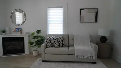 a living room with a couch and a mirror at Water View - Modern Cottage in Niagara-on-the-Lake in Niagara on the Lake