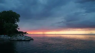 a sunset over a body of water with a rainbow at Water View - Modern Cottage in Niagara-on-the-Lake in Niagara on the Lake
