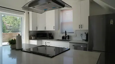 a kitchen with white cabinets and a black refrigerator at Water View - Modern Cottage in Niagara-on-the-Lake in Niagara on the Lake