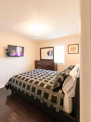 a bedroom with a bed and a tv on the wall at WALK TO THE BEACH in Fort Erie