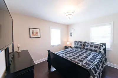 a bedroom with a bed and a dresser and windows at WALK TO THE BEACH in Fort Erie