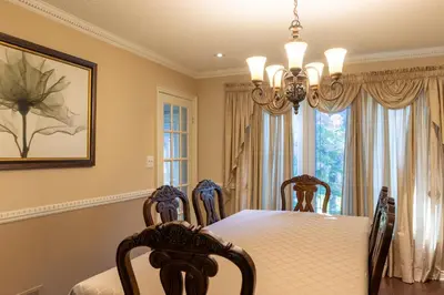 a dining room with a table and chairs and a chandelier at Elegant Mansion with Private Bar & Game Lounge in Mississauga