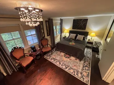 a bedroom with a bed and two chairs and a chandelier at Vintage Pines Guest House in Niagara on the Lake