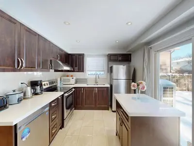 a large kitchen with wooden cabinets and a large window at Cozy Queen room with Shared Bath near Seneca Finch 404 in Toronto