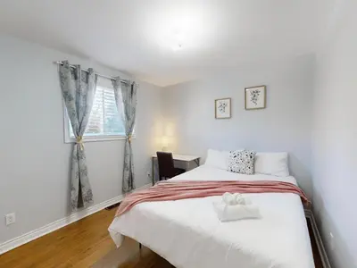 a bedroom with a large bed and a window at Cozy Queen room with Shared Bath near Seneca Finch 404 in Toronto