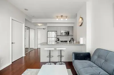 a living room with a couch and a kitchen at 1 Bedroom Condo Burano Downtown Toronto in Toronto