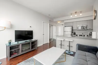 a living room with a couch and a tv and a kitchen at 1 Bedroom Condo Burano Downtown Toronto in Toronto