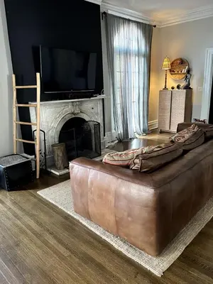 a large brown leather couch in a living room with a fireplace at 1Br Apt In Mansion With Indoor Pool Hot Tub in Hamilton