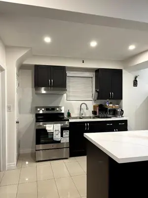a kitchen with black cabinets and a stove top oven at Cozy 2-Bed with Kitchen and Patio in Midtown Toronto in Toronto