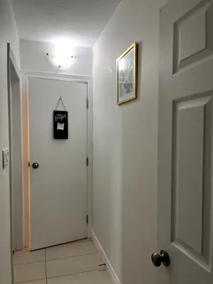 a hallway with a white door and a picture on the wall at Cozy 2-Bed with Kitchen and Patio in Midtown Toronto in Toronto