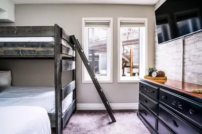 a bedroom with a bunk bed and two windows at Easy Rider Chalet Steps to Lift & Blue Village in Blue Mountains