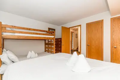 a bedroom with a white bed and a bunk bed at Chateau Ridge Retreat - Ski-In Ski-Out Winter Fun in Blue Mountains