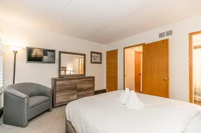 a bedroom with a bed and a chair and a mirror at Chateau Ridge Retreat - Ski-In Ski-Out Winter Fun in Blue Mountains
