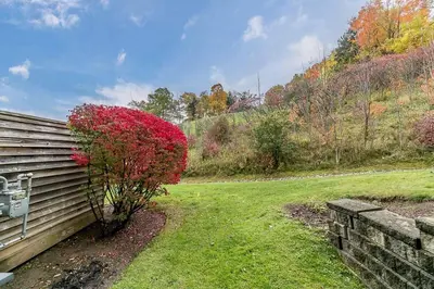 a house with a red bush next to a wall at Chateau Ridge Retreat - Ski-In Ski-Out Winter Fun in Blue Mountains