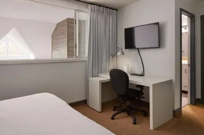 a hotel room with a desk and a bed and a television at First Tracks Ski-In Ski-Out & Walk to Village in Blue Mountains
