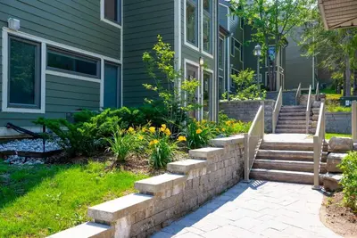 a house with a retaining wall and stairs in the yard at Hillside Lookout - Ski-In Ski-Out Alpine Escape in Blue Mountains