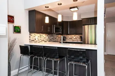 a kitchen with black cabinets and a counter with stools at Hillside Lookout - Ski-In Ski-Out Alpine Escape in Blue Mountains