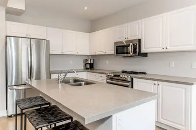 a kitchen with white cabinets and a stainless steel refrigerator at Modern Luxury Townhome Walk to Blue Shuttle in Blue Mountains