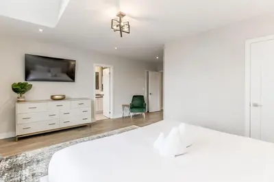 a white bedroom with a bed and a dresser at Modern Luxury Townhome Walk to Blue Shuttle in Blue Mountains