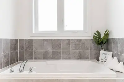 a white bath tub in a bathroom with a window at Modern Luxury Townhome Walk to Blue Shuttle in Blue Mountains