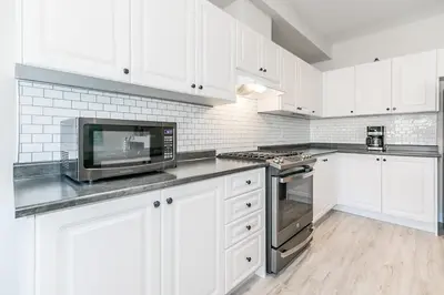 a kitchen with white cabinets and a microwave at Family Townhouse Walk-Shuttle to Blue Fire Pit in Blue Mountains