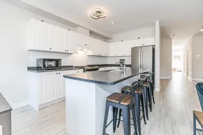 a kitchen with white cabinets and a counter with stools at Family Townhouse Walk-Shuttle to Blue Fire Pit in Blue Mountains
