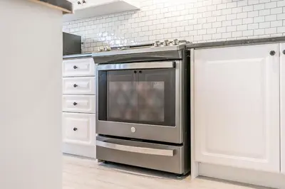 a kitchen with a stainless steel stove and white cabinets at Family Townhouse Walk-Shuttle to Blue Fire Pit in Blue Mountains