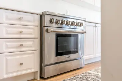 a stainless steel oven in a kitchen with white cabinets at Blue Mtn Village Retreat Walk to Blue - Shuttle in Collingwood