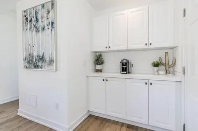 a white kitchen with white cabinets and a picture at Blue Mtn Village Retreat Walk to Blue - Shuttle in Collingwood