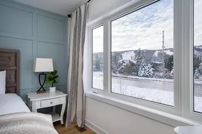 a bedroom with a bed and a large window at Blue Mtn Village Retreat Walk to Blue - Shuttle in Collingwood