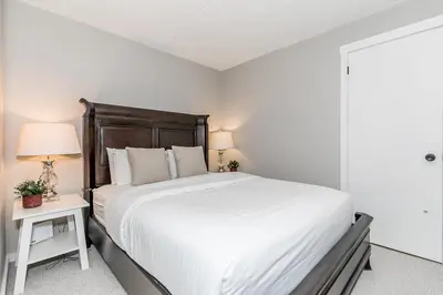 a white bedroom with a large bed and a table at Alpine Cove - Condo in Collingwood - Sleeps 6 in Collingwood