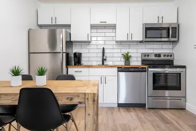 a kitchen with stainless steel appliances and a wooden table at The Fox Den - Modern Condo Collingwood - Sleeps 5 in Collingwood