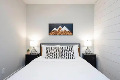 a bedroom with a white bed and two lamps at The Fox Den - Modern Condo Collingwood - Sleeps 5 in Collingwood