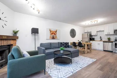 a living room with a blue couch and a kitchen at The Fox Den - Modern Condo Collingwood - Sleeps 5 in Collingwood