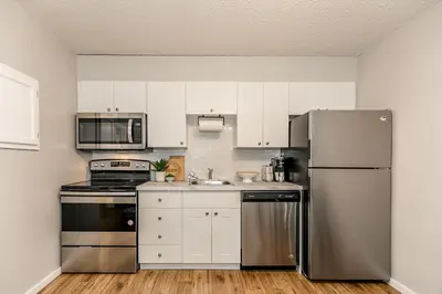 a kitchen with white cabinets and a stainless steel refrigerator at South Wind - Modern Condo in Collingwood - Sleep 5 in Collingwood