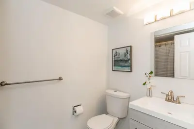 a white bathroom with a toilet and a sink at The Nest - Walk to Blue Private Patio in Blue Mountains