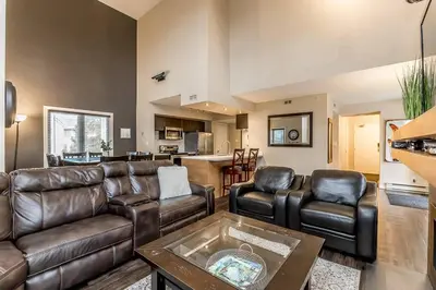 a living room with leather furniture and a kitchen at Mountain Walk Retreat - Walk to Blue Patio area in Blue Mountains