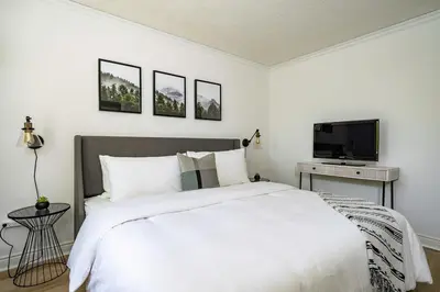 a bedroom with a white bed and a tv at Sweet Retreat Ski-In Ski-Out - Pool & Hot Tub in Blue Mountains